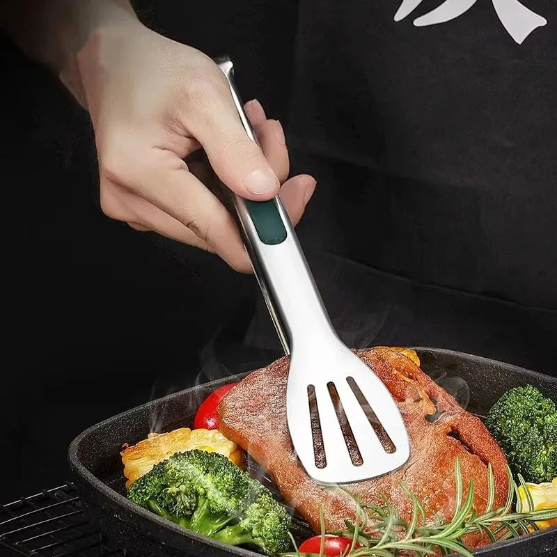 Person using a stainless steel spatula to flip a steak on a grill with vegetables.