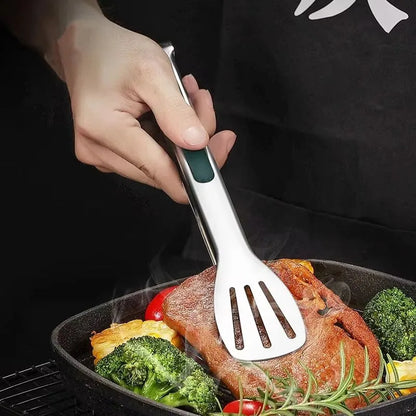 Person using a stainless steel spatula to flip a steak on a grill with vegetables.