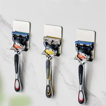 Three razors attached to a wall-mounted metal holder on a marble surface.