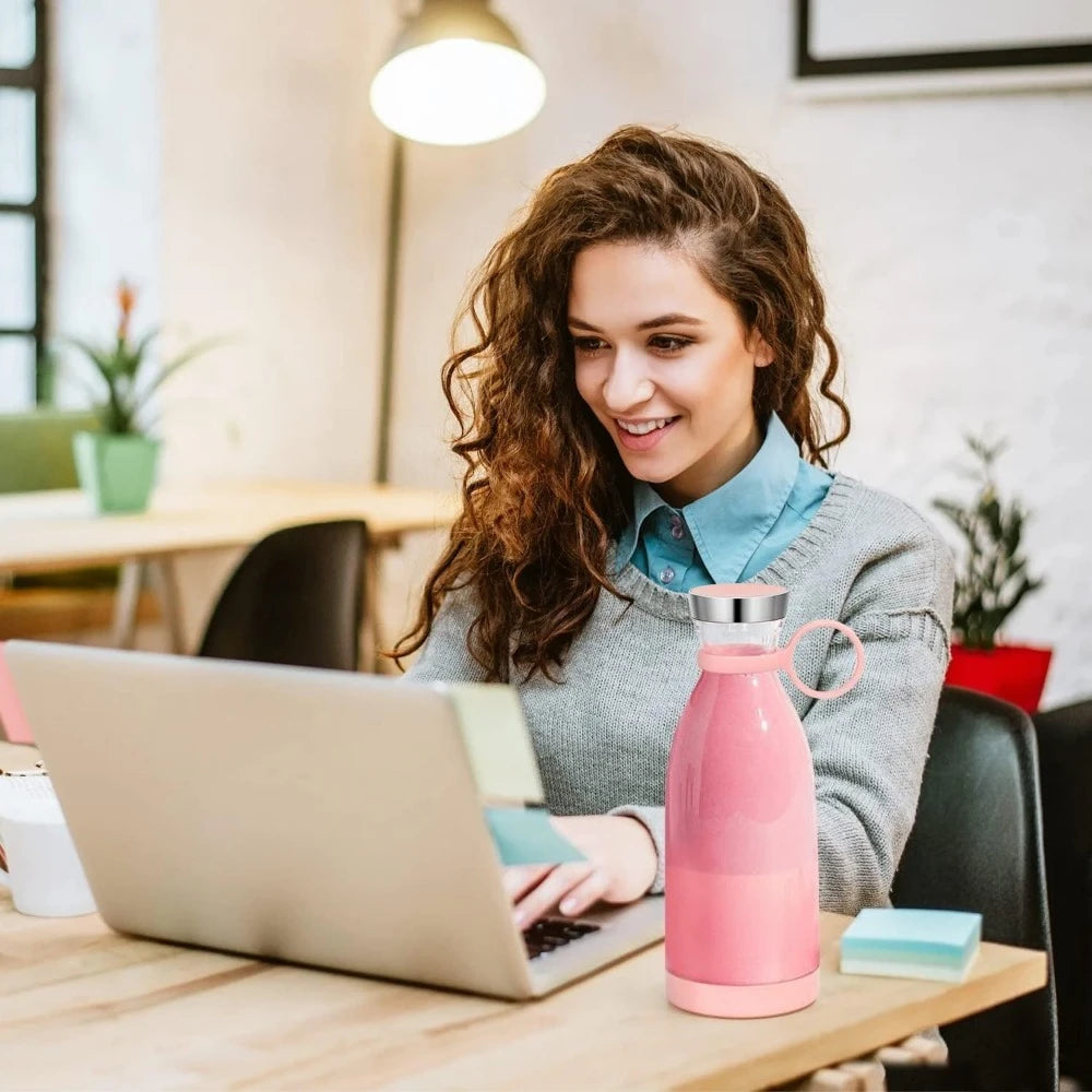 Woman using a laptop with a pink water bottle on a desk in an office setting