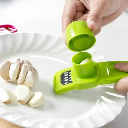 Green garlic peeler being used on a white plate with garlic cloves.