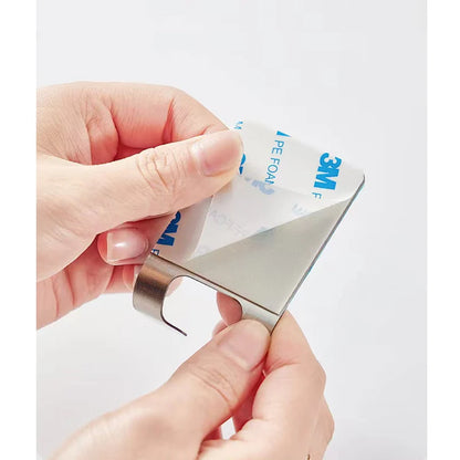 Metal tool with 3M adhesive strip being used on a white background