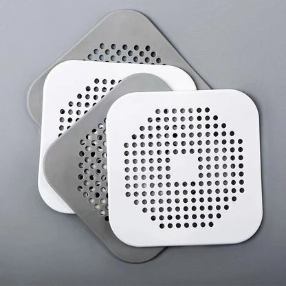 Two white square filters with perforated designs on a gray background