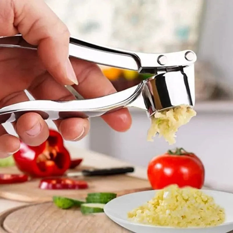 Garlic press being used to crush garlic with a blurred kitchen background