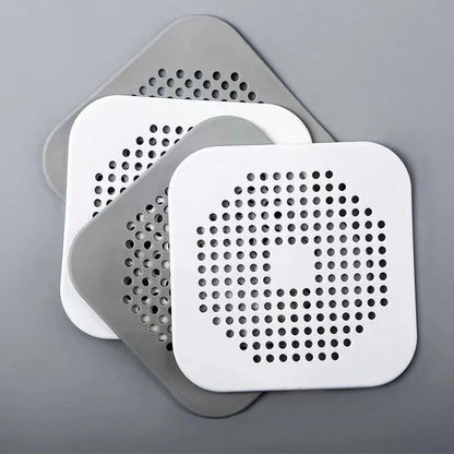 Two white square filters with perforated designs on a gray background
