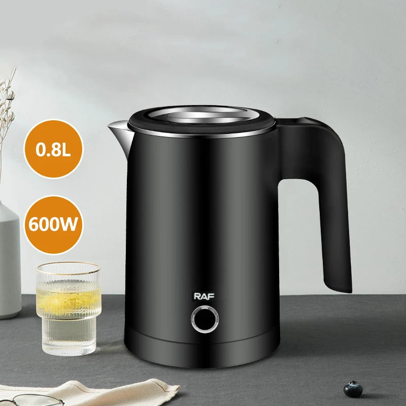 Black electric kettle withRAF branding on a gray surface, next to a glass of liquid.