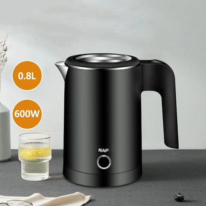 Black electric kettle withRAF branding on a gray surface, next to a glass of liquid.